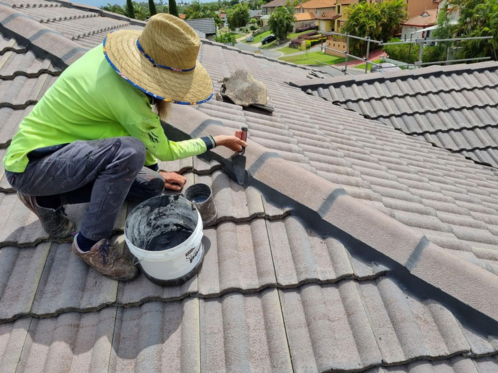Roofer repointing a ridge cap on a tile roof